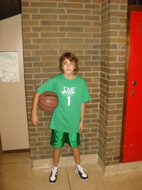 a  holding a basketball next to a brick wall