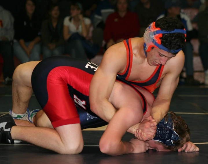 a wrestler in red and blue is knocked by a wrestler