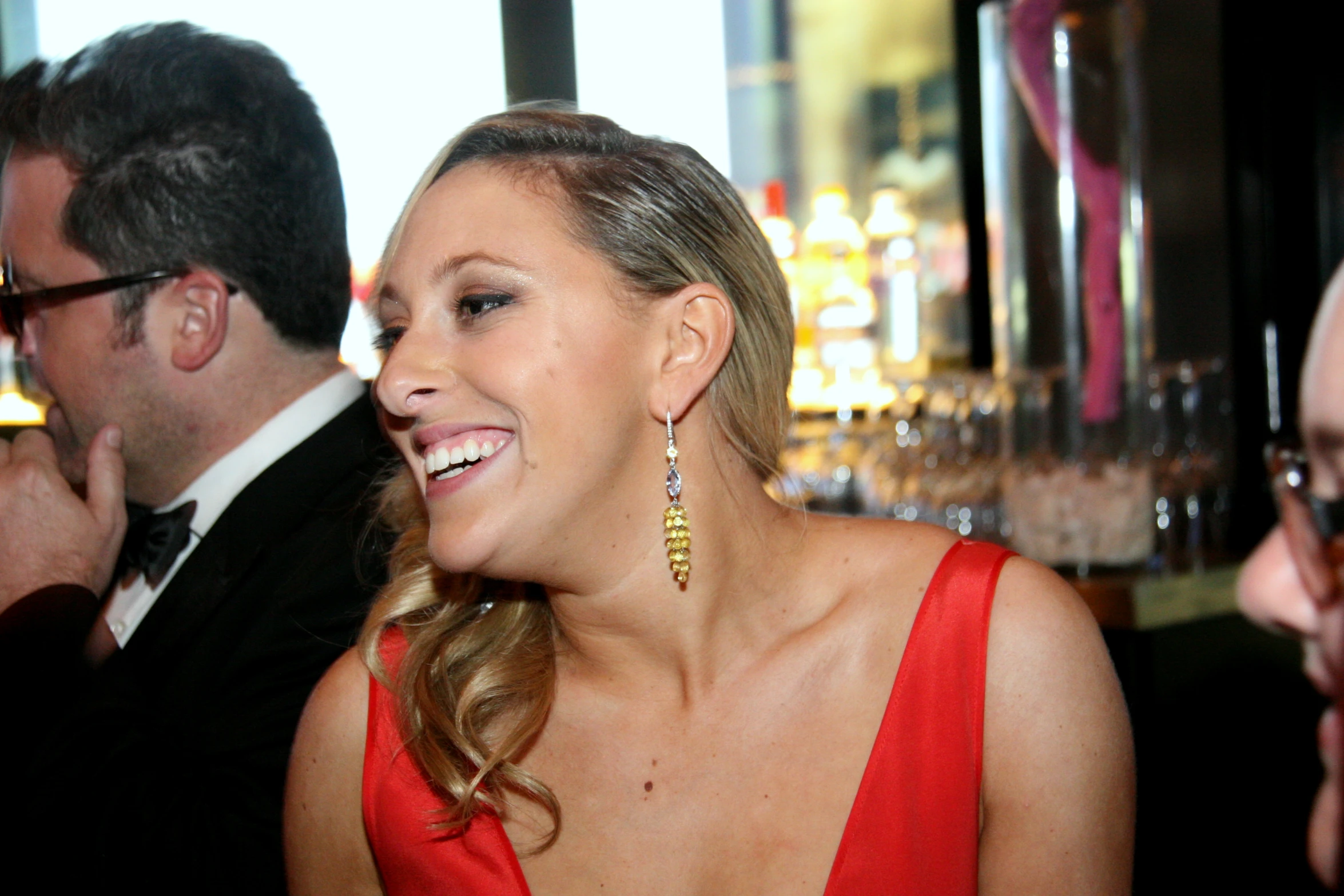 two people are having drinks and a woman is wearing a red dress