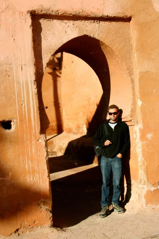 a man standing outside a large doorway with his arms crossed