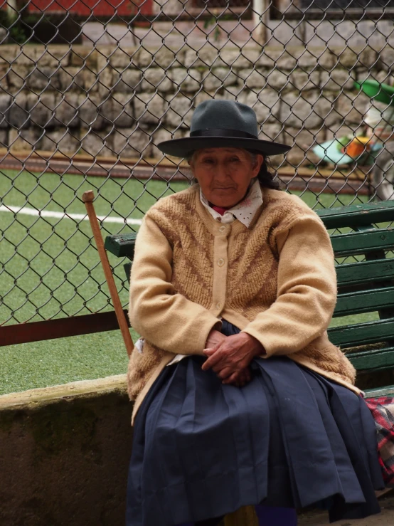 an older woman sitting on top of a green bench