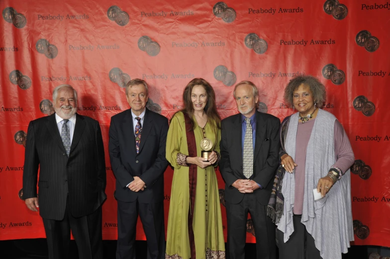 the four people in front of a red banner pose with an award