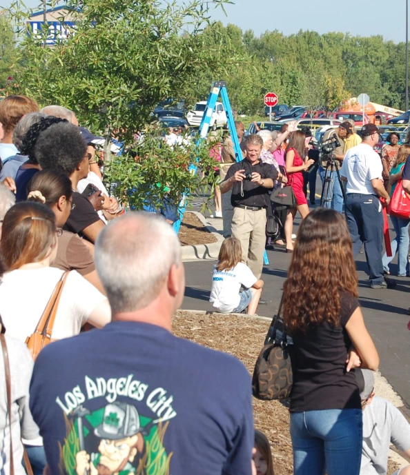 a crowd of people walking around a field with trees in the background