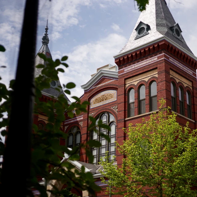 a very large building has a clock tower and some trees