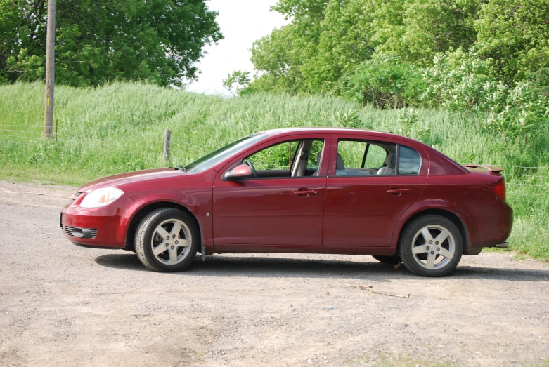 a red car parked next to a country road