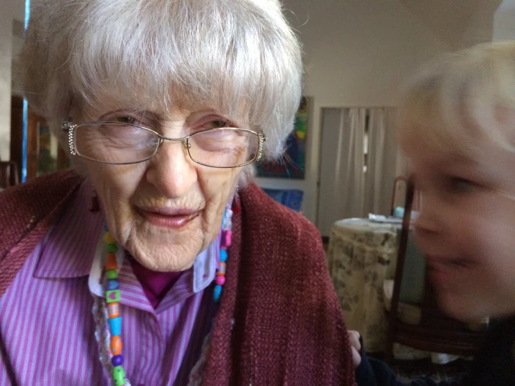 an elderly lady wearing glasses talking to another woman