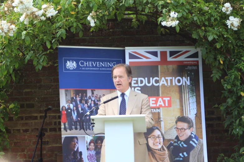 a man is standing in front of a poster that reads education