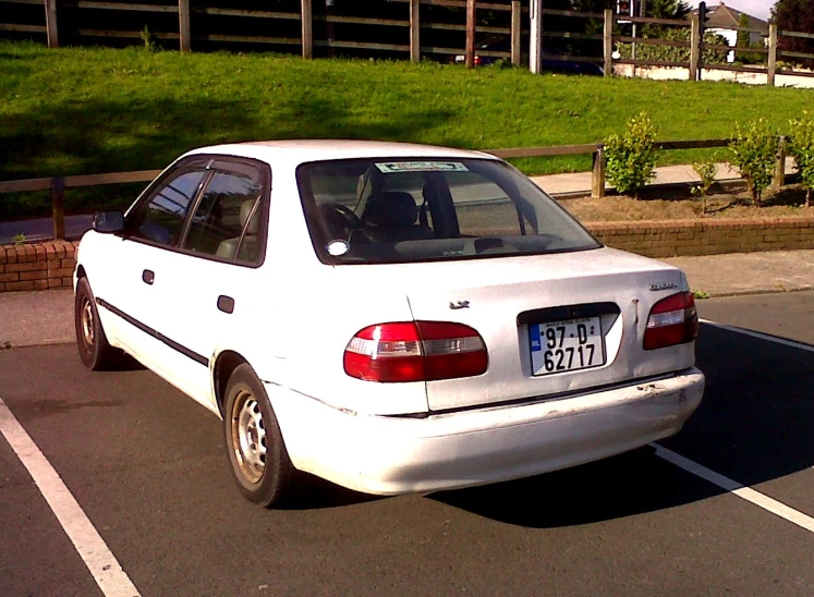 white car sitting in the middle of a parking lot