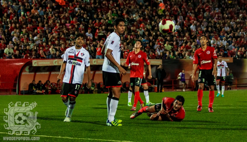 a player falls onto the ground as another soccer player lies down in front of him