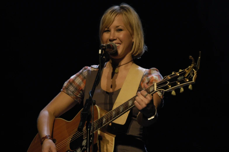 a woman that is holding an acoustic guitar