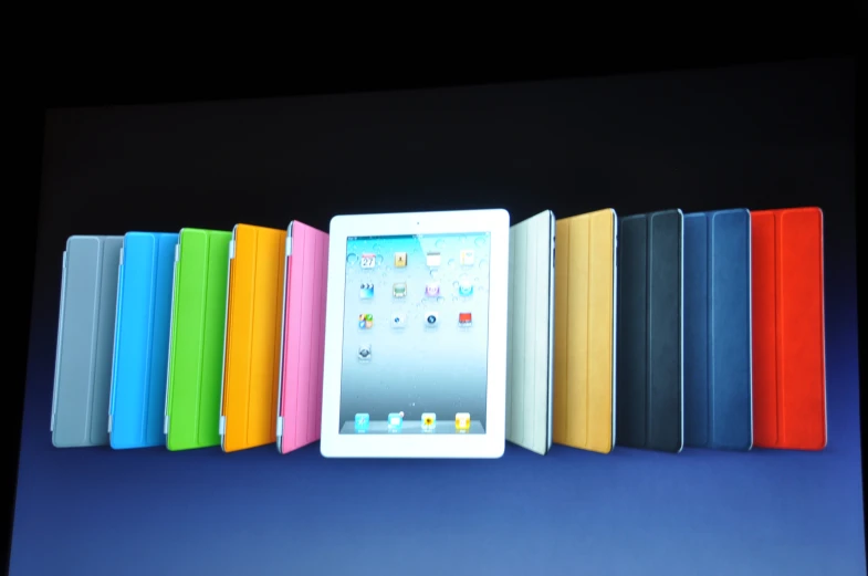 an ipad is seen next to a row of colored books