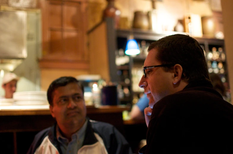 two men having conversation at a small bar