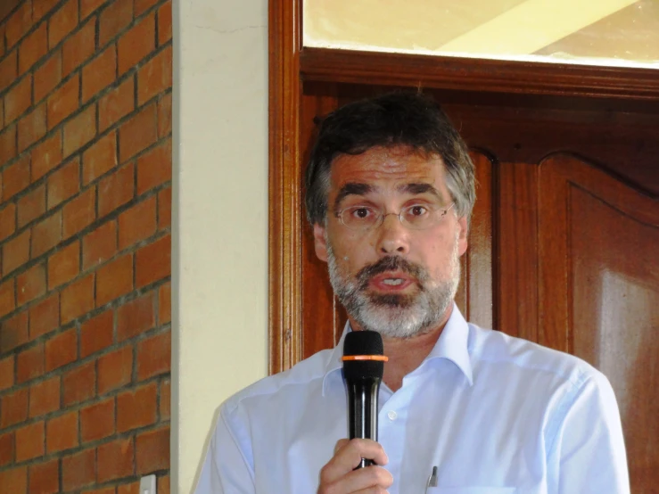 a man holding up a microphone on a brick wall