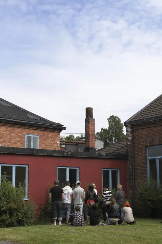 five people are standing outside of a red building