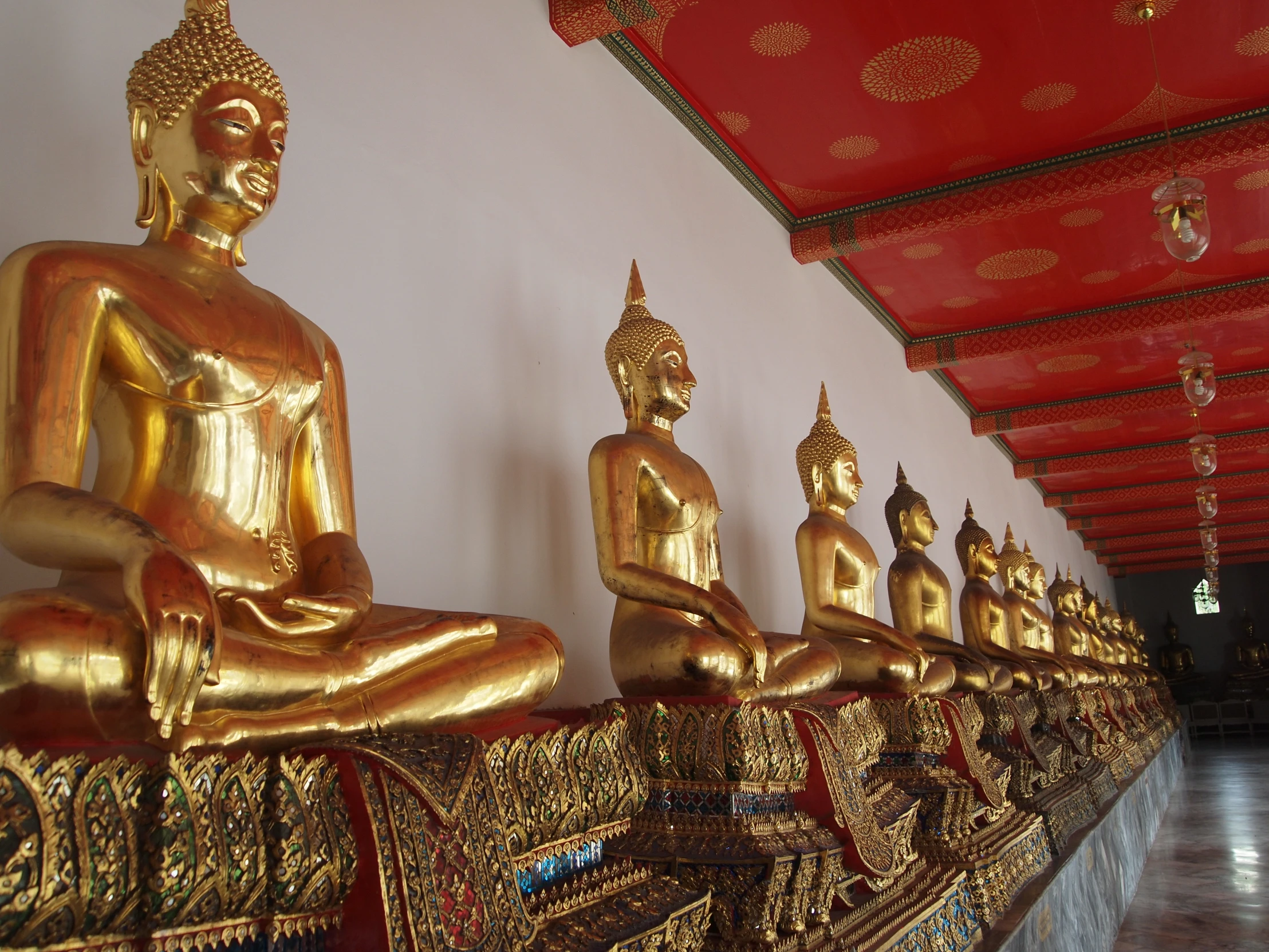 many gold buddha statues are on display in a room