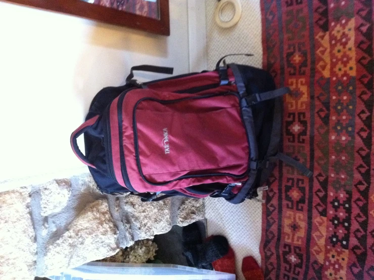 a red and black back pack on the floor