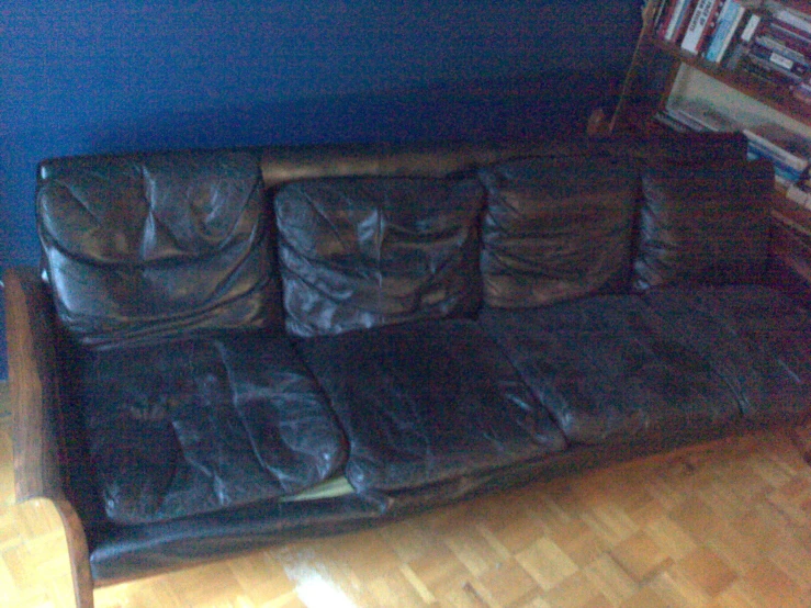 a leather couch in a corner with a wooden floor