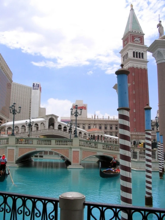 a large clock tower over water with a bridge in the background