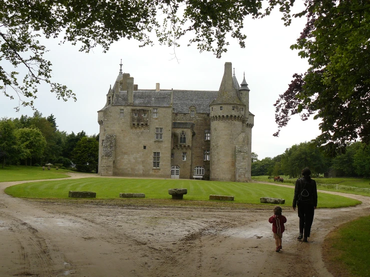 a person and their child walking in the rain by an old building