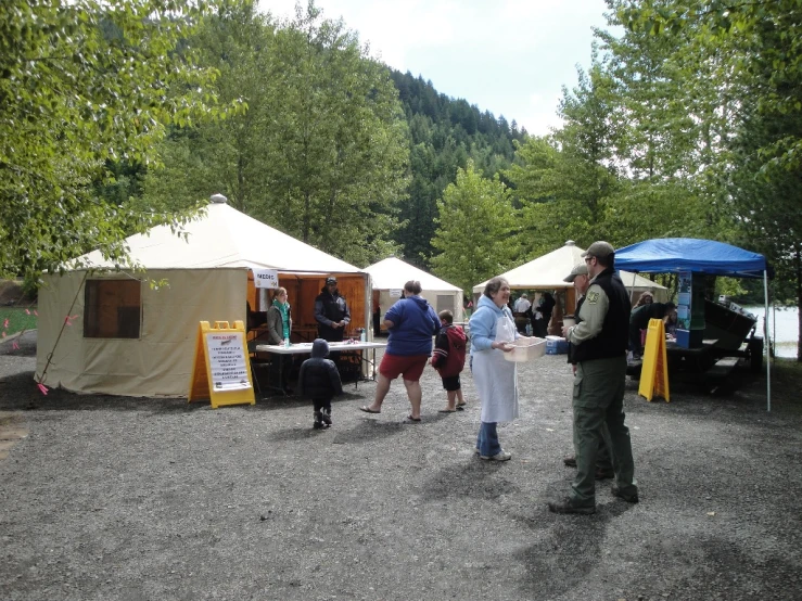 a man standing under an open tent next to a forest