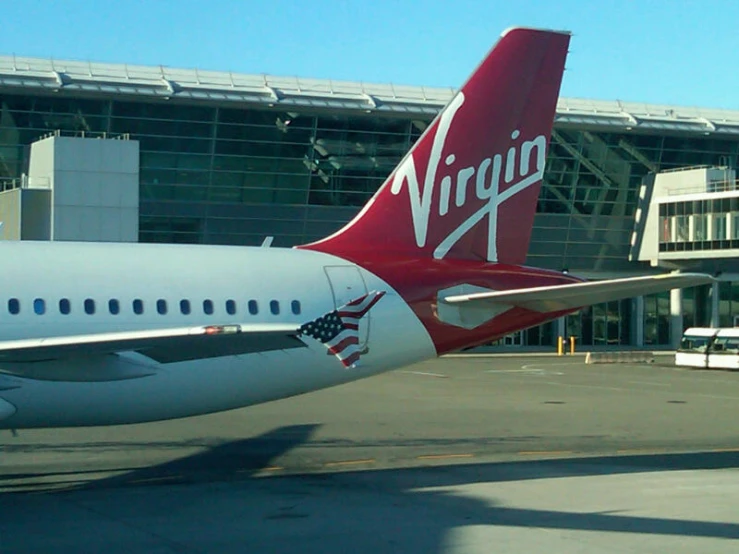 the tail end of an airplane sits parked in front of a terminal