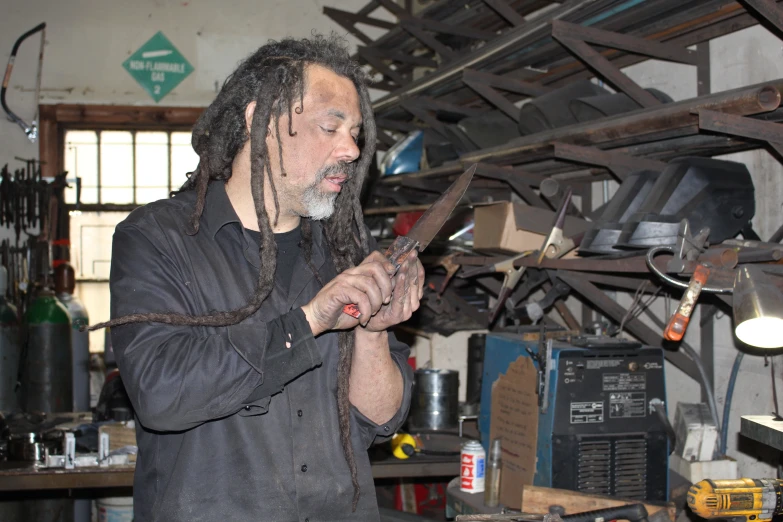 a man in a workshop holding a large pair of scissors