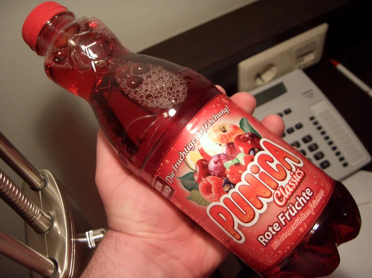 a person holds a bottle of budda popple fruit drink