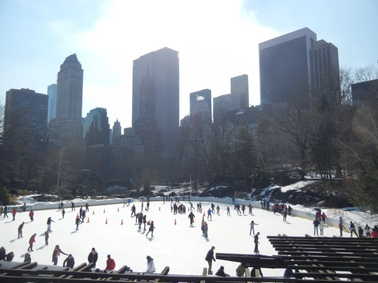 people ice skating in the snow in a city park