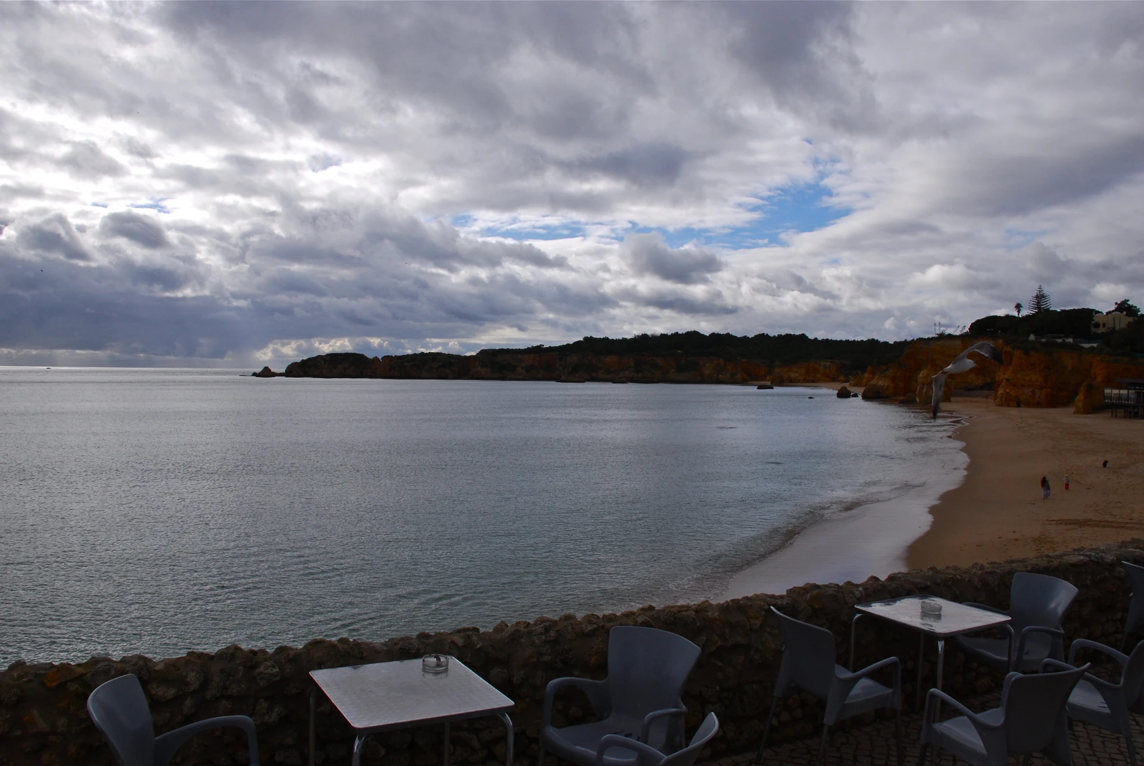 empty table and chairs in front of the beach