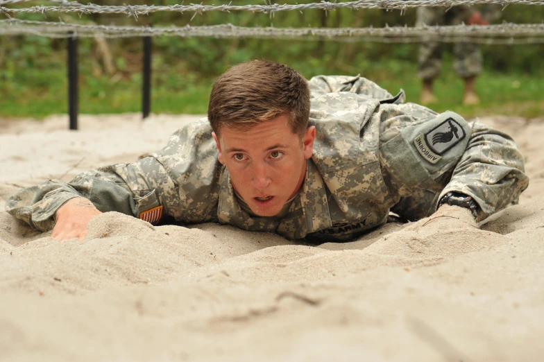 a military man in the sand with his hand on the ground