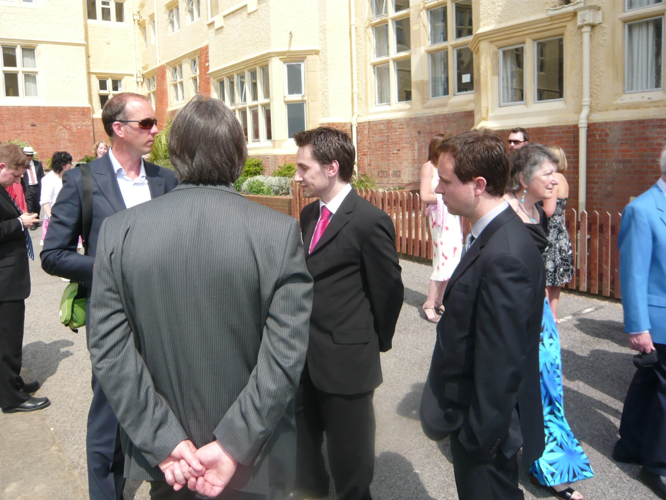 a group of men are in suits walking towards a building