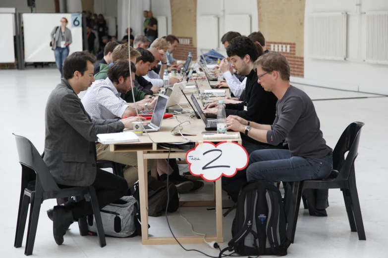 people sitting around a table using laptops