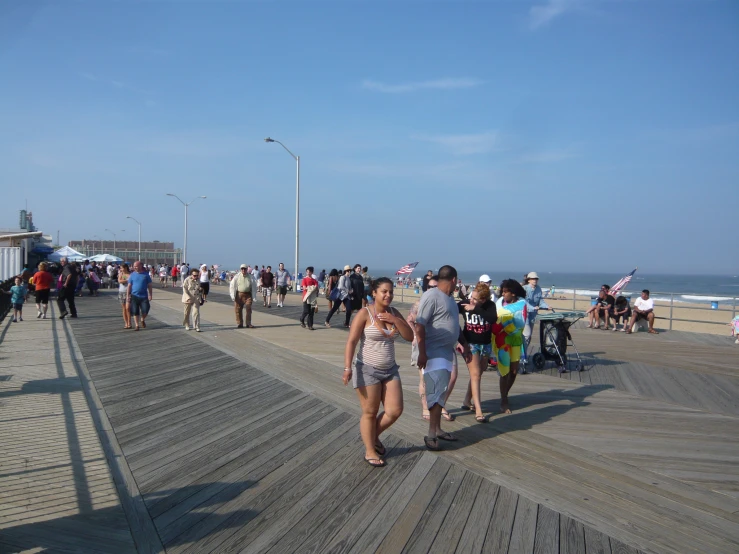 the people are walking on the boardwalk by the water
