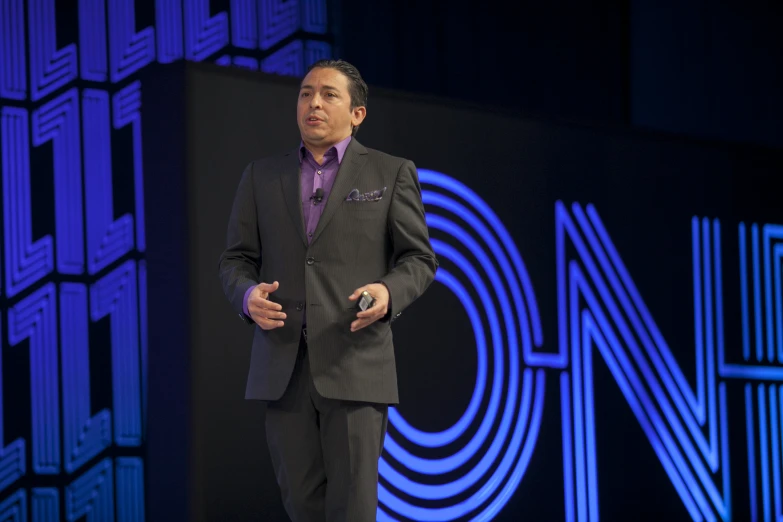 man wearing black suit at an on stage presentation