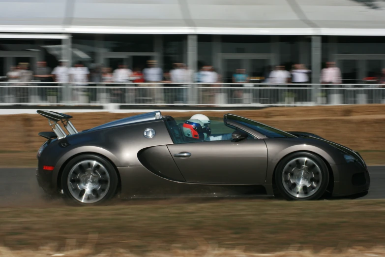 a sports car speeds around a course while spectators look on