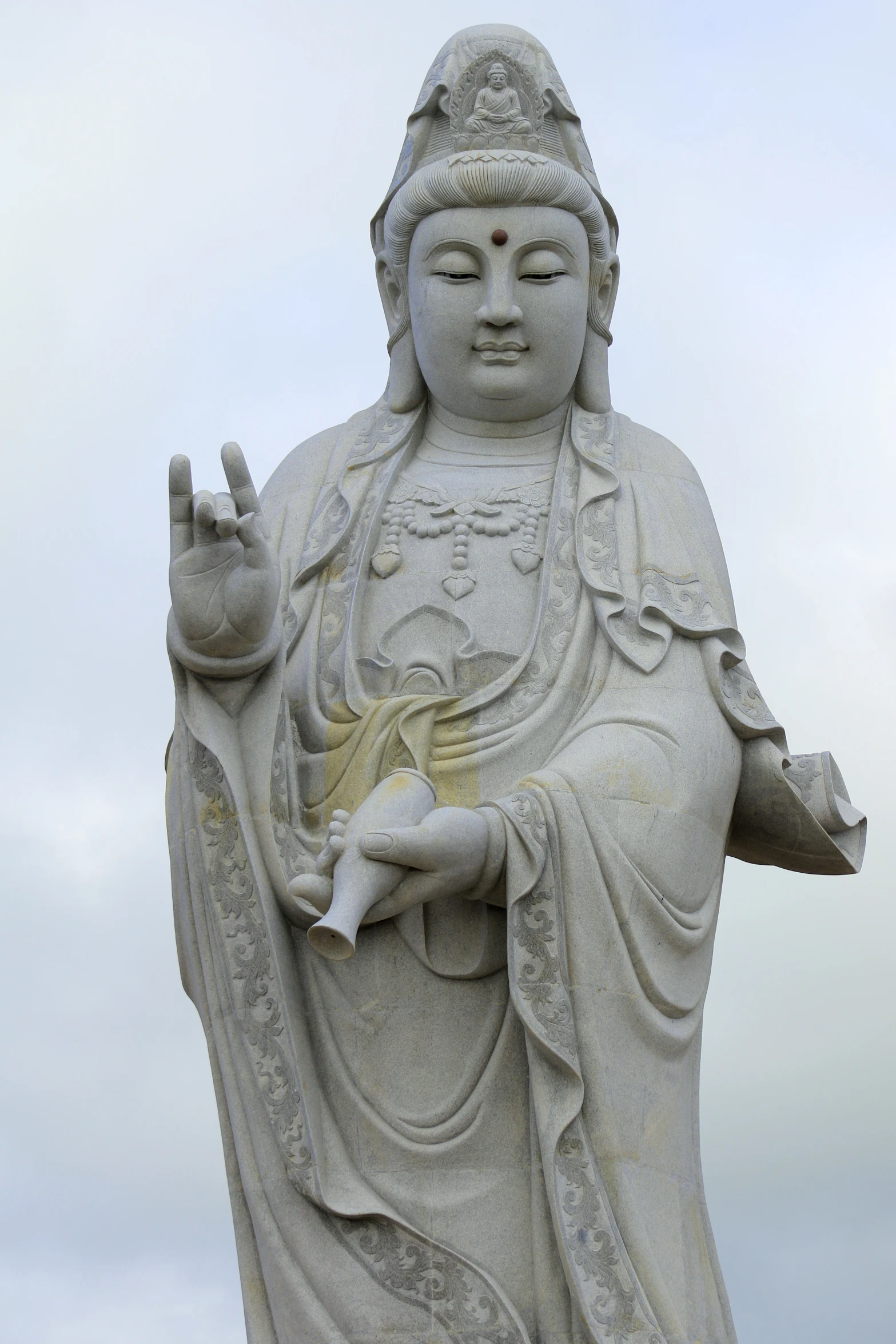 an intricately carved buddha statue against a cloudy blue sky