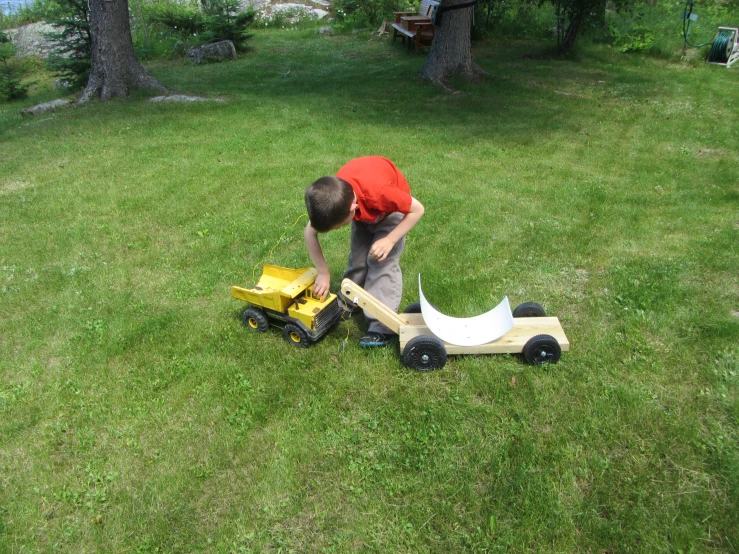 a small child playing with toy trucks on green grass