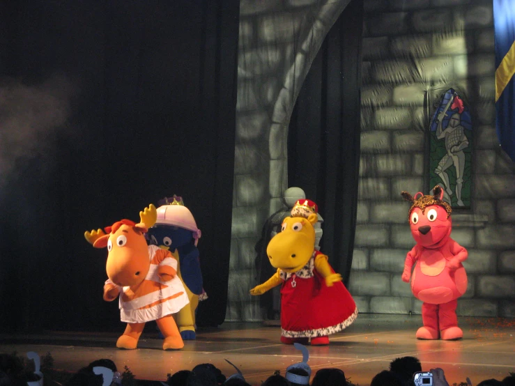 three cartoon characters are wearing costumes in front of people