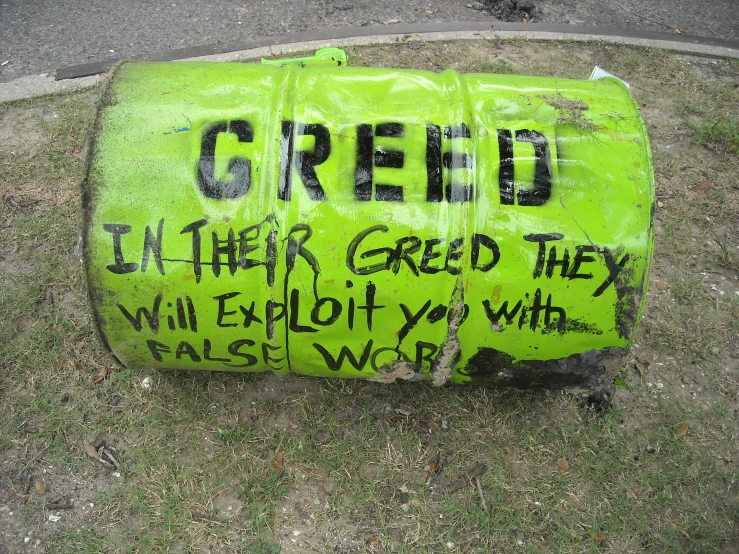 a green plastic sign with graffiti on it