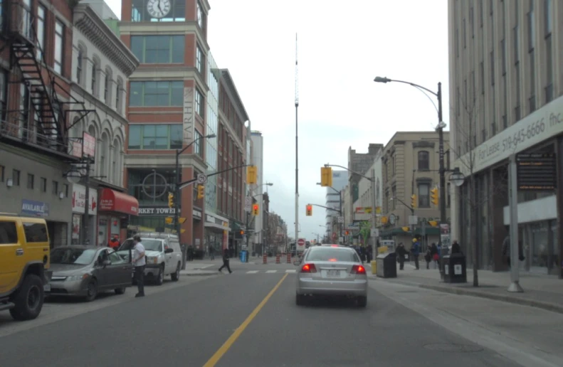 there is a street with cars driving by buildings