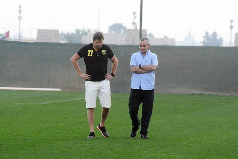 a male soccer player in black and a female in white are standing in a field