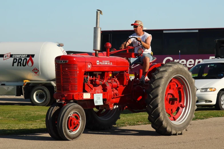 a man is sitting on a tractor in front of a tanker