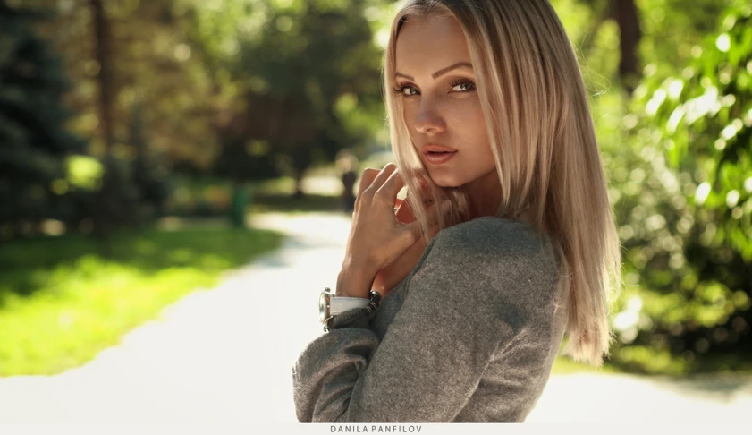 a woman looking away, with trees in the background