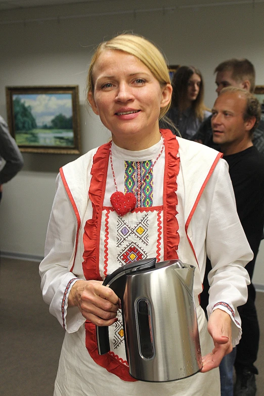 a woman holding a silver pitcher in her hand