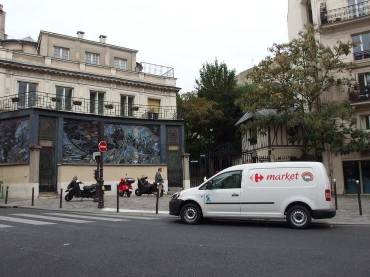 a white van parked near a tall building with a mural on the side of it