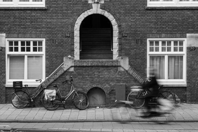 man riding bicycle past three parked bikes on a city street