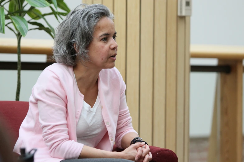 an older woman sits in a chair and looks off to the side