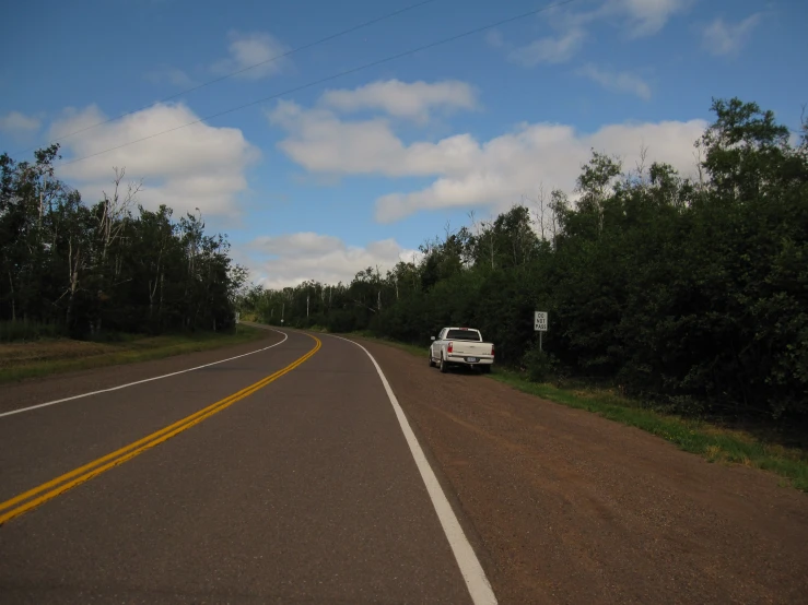 a white truck is driving down the middle of a road