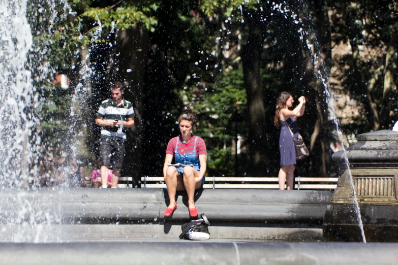 people are standing in front of fountains on the side of a street