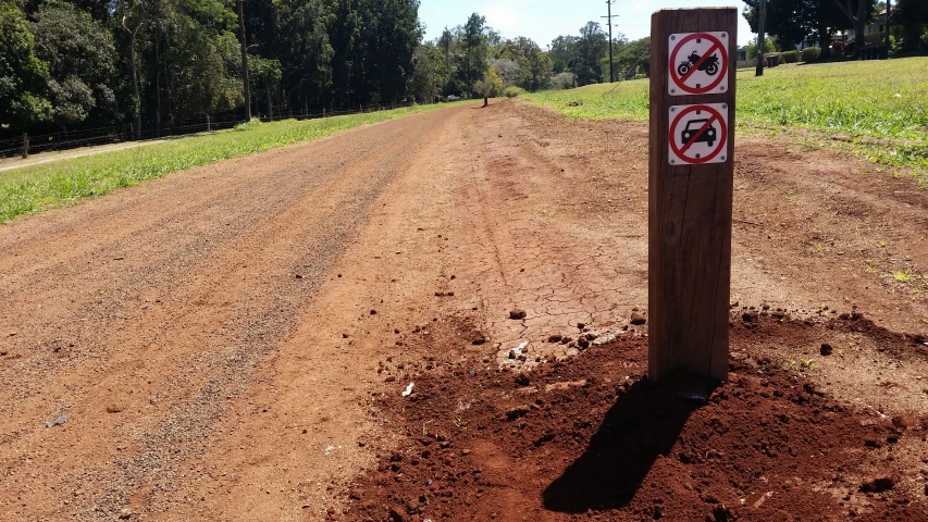 a no stopping sign by a dirt road in the middle of a field